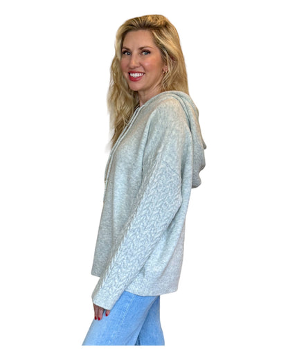 Model wearing an Antique Rose Women's Hoodie featuring wide cable-knit braided sleeves, a cozy marled sweater knit bodice, and an oversized fit.