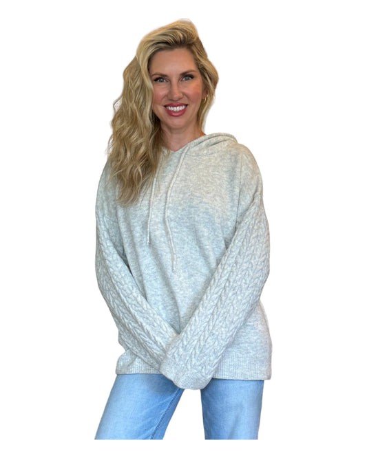 Model wearing the Grey Mist Women's Hoodie featuring wide cable-knit braided sleeves, a cozy marled sweater knit bodice, and an oversized fit.