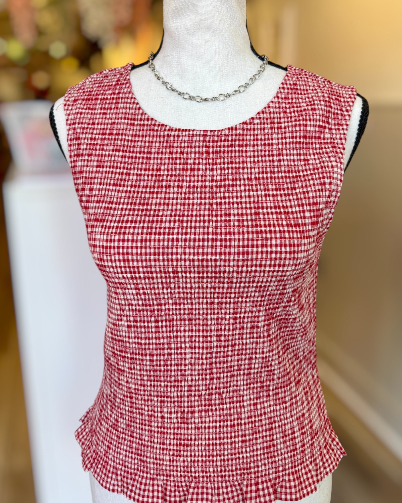 Red and white checkered top on a mannequin with a blurred background.