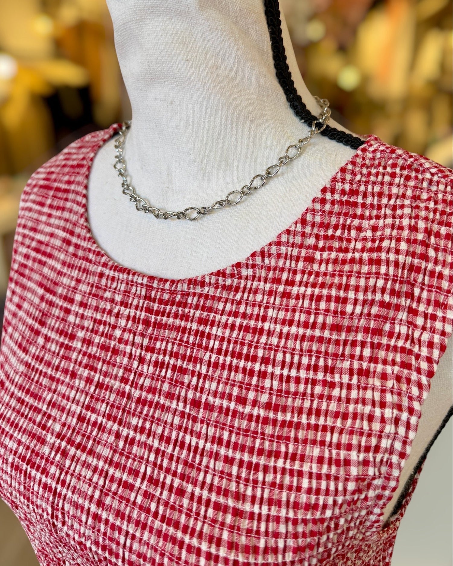 Red and white checkered top on a mannequin with a blurred background.