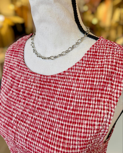 Red and white checkered top on a mannequin with a blurred background.