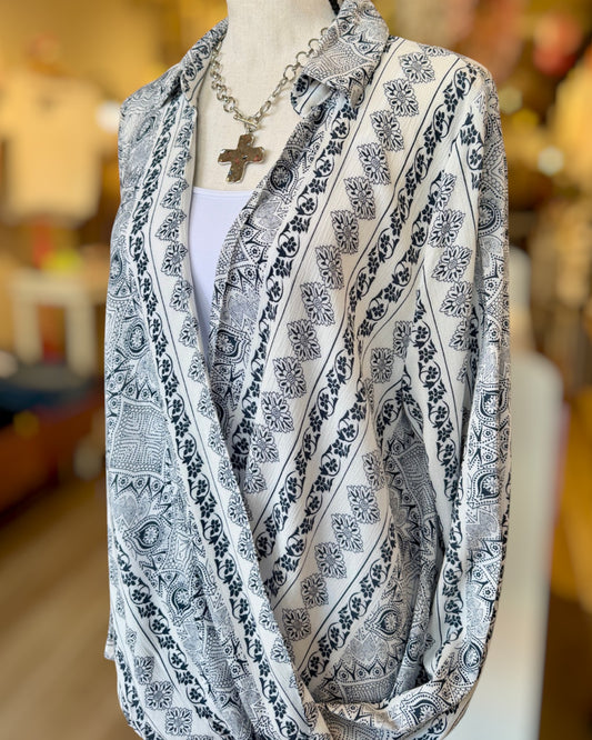Mannequin wearing a navy and ivory patterned wrap top with a blurred indoor background.