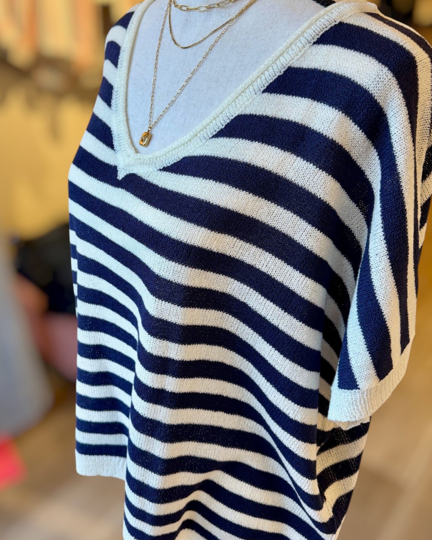 Navy and white striped sweater on a mannequin with a blurred background.