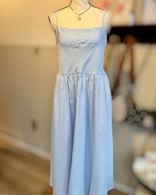Blue and white striped dress on a mannequin against a blurred indoor background.
