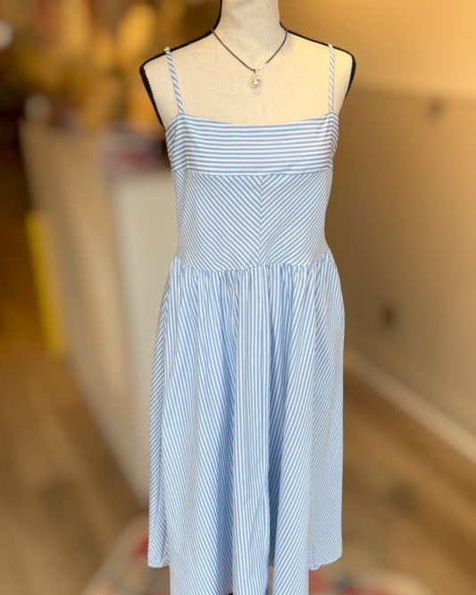 Blue and white striped dress on a mannequin with a blurred background.