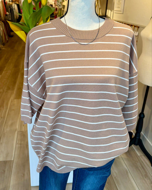 Mannequin wearing a taupe and white striped sweater and jeans in a store setting. 