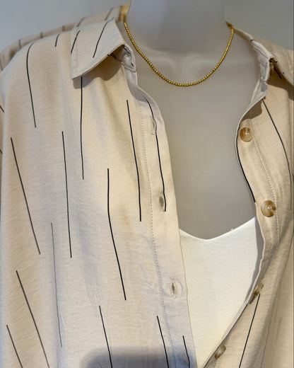 Mannequin wearing a beige shirt with black vertical stripes on a plain background