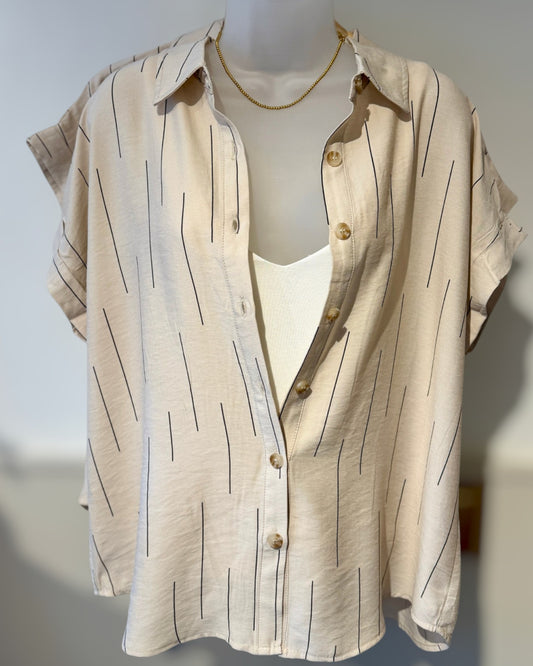 Beige shirt with a subtle line pattern on a mannequin against a plain background.