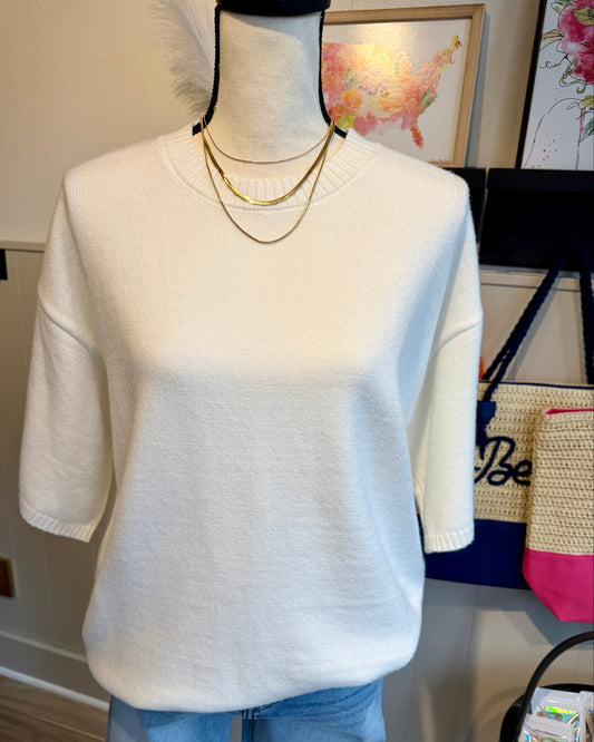 Mannequin wearing a white sweater with 3/4 sleeves and blue jeans.