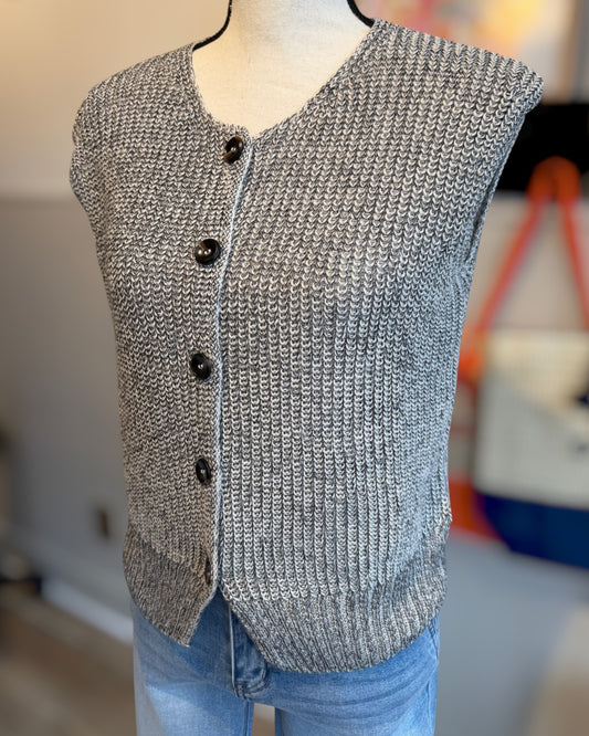 Gray knitted sleeveless vest on a mannequin with a blurred indoor background.