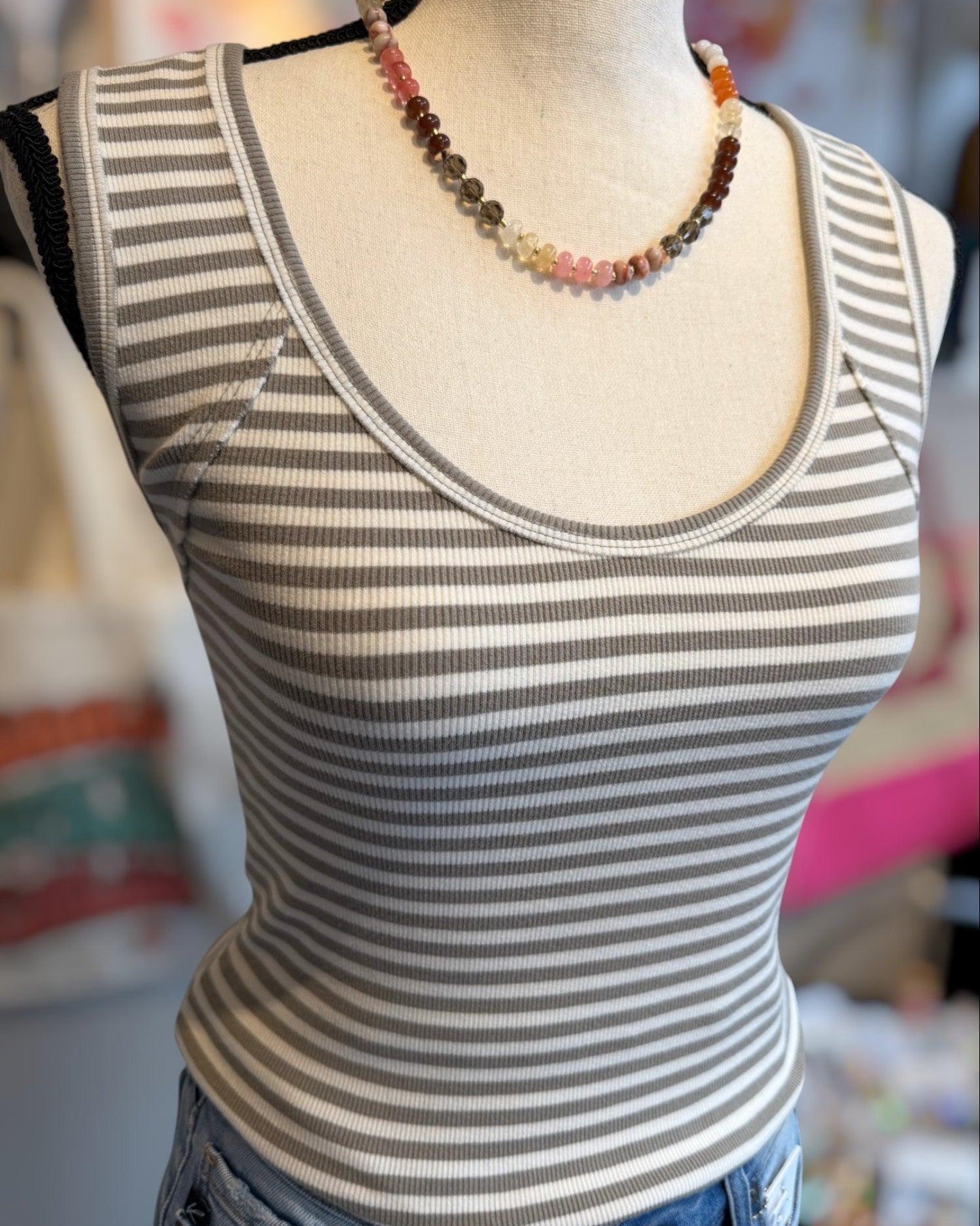 Striped tank top on a mannequin with a blurred background.