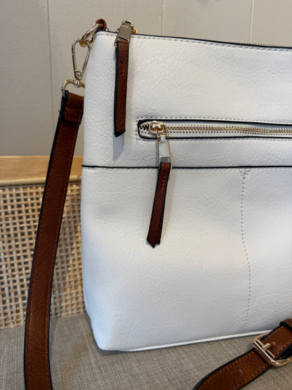 A white textured leather handbag with brown leather straps and gold-tone hardware, shown in a close-up shot against a neutral background.