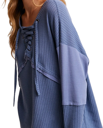 Blue textured top with lace-up detail on a white background.
