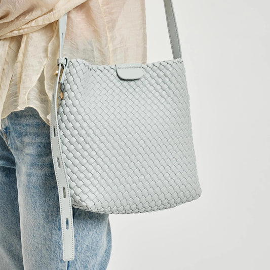 Light gray/ice blue woven handbag worn over the shoulder with a neutral background.