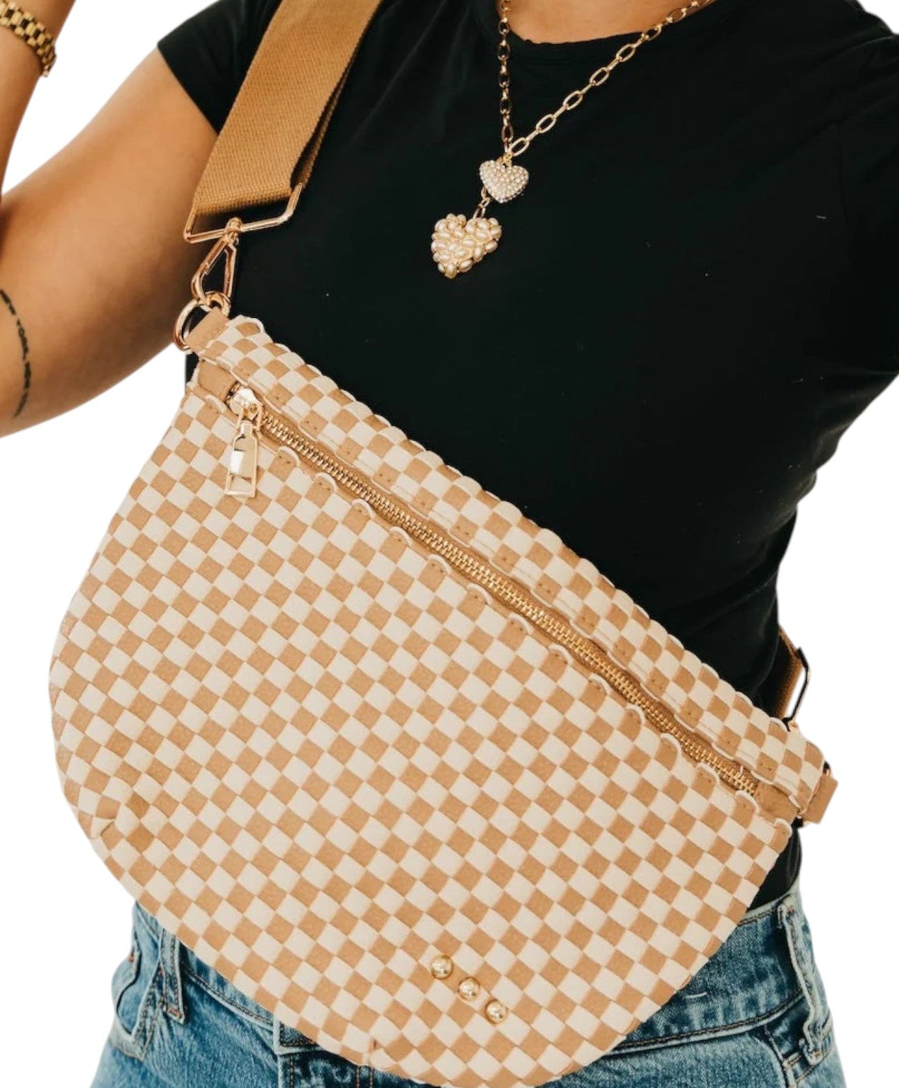 Person wearing a beige checkered bum bag with a black top and blue jeans on a white background.