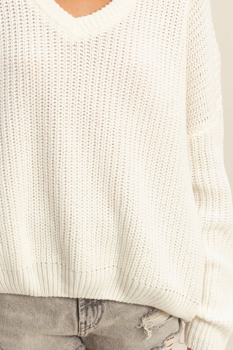Close-up of a person wearing a white textured sweater with a neutral background.