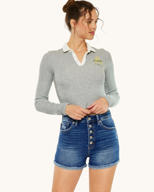 Woman wearing a gray long-sleeve shirt with a collar and denim shorts on a white background.