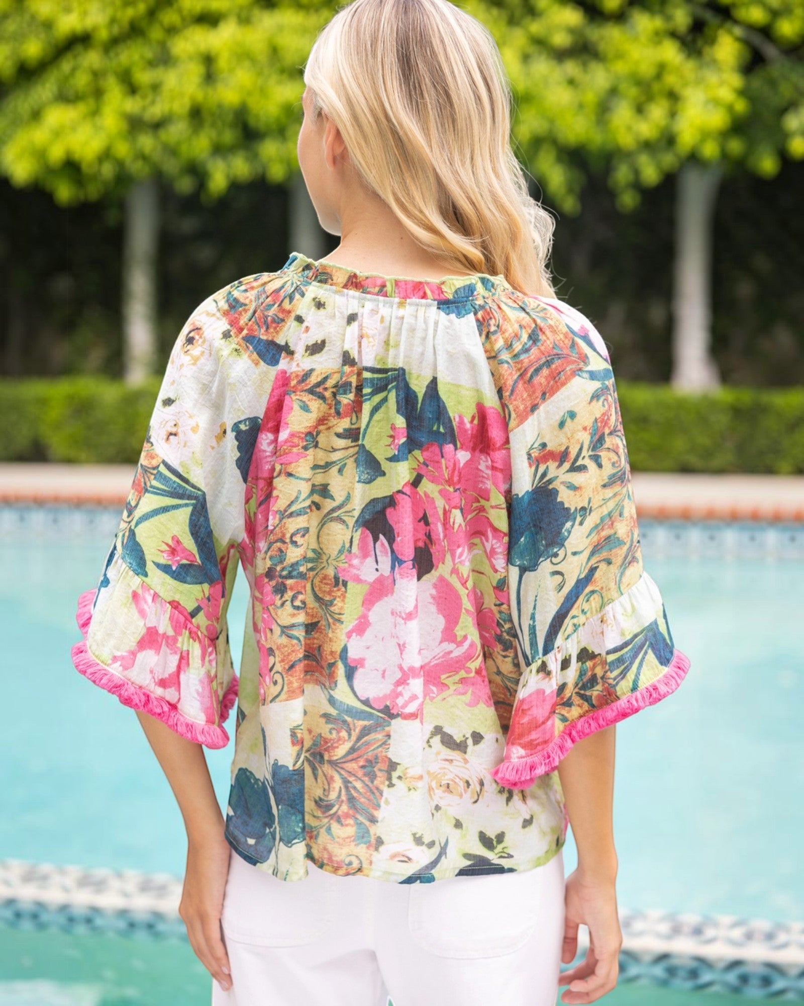 Back view of a woman wearing a floral blouse by a poolside.