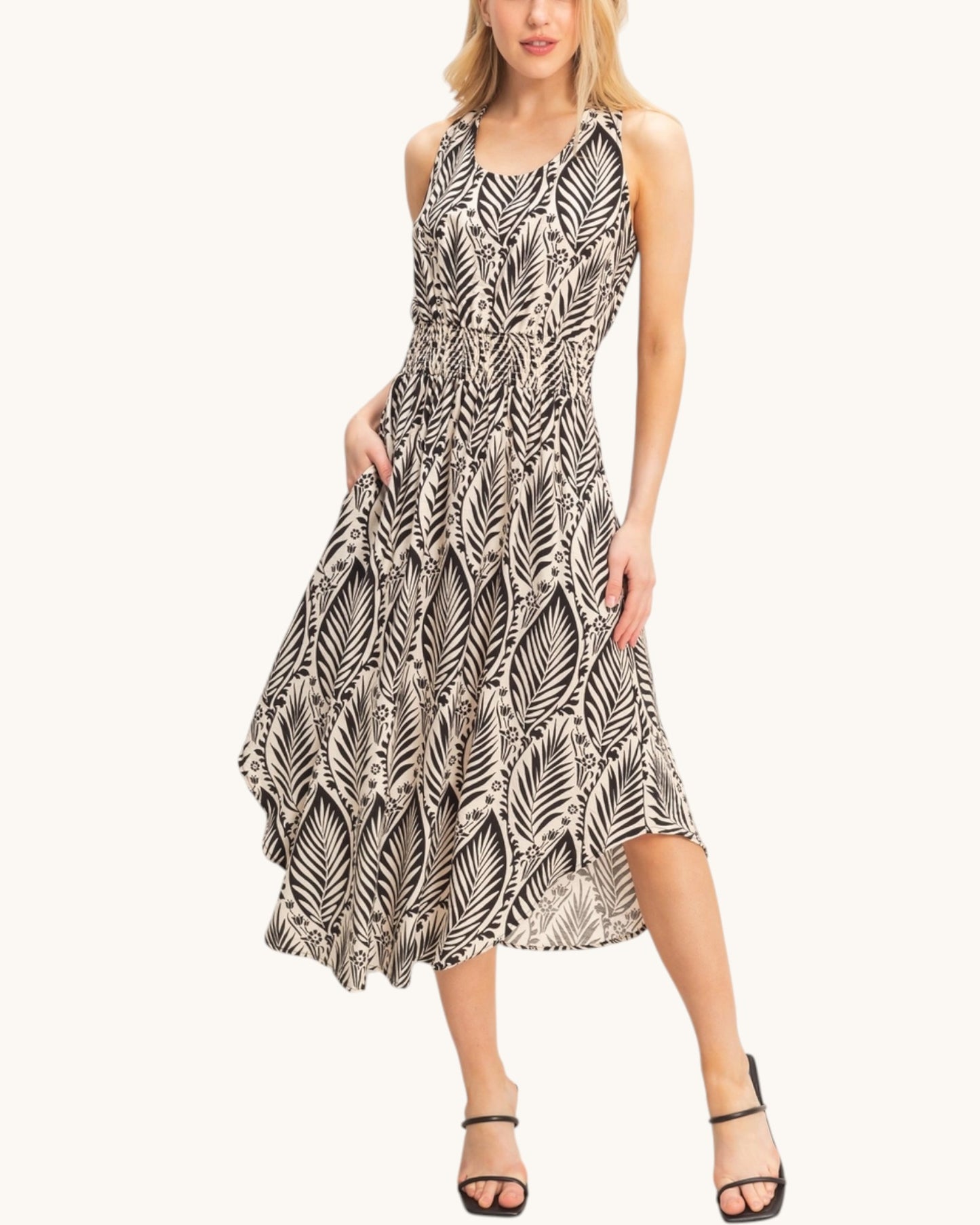 Woman wearing a beige sleeveless dress with a black leaf pattern on a white background.