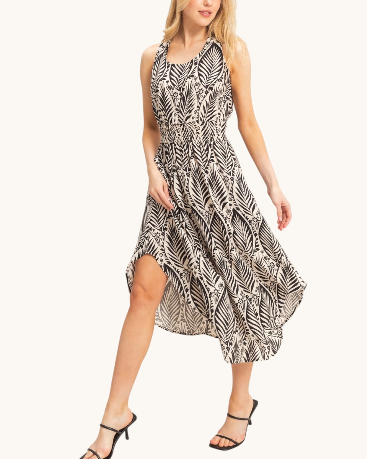 Woman wearing a black and beige leaf patterned dress on a white background.