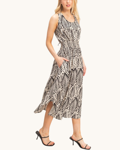 Woman wearing a sleeveless dress with a leaf pattern on a white background.