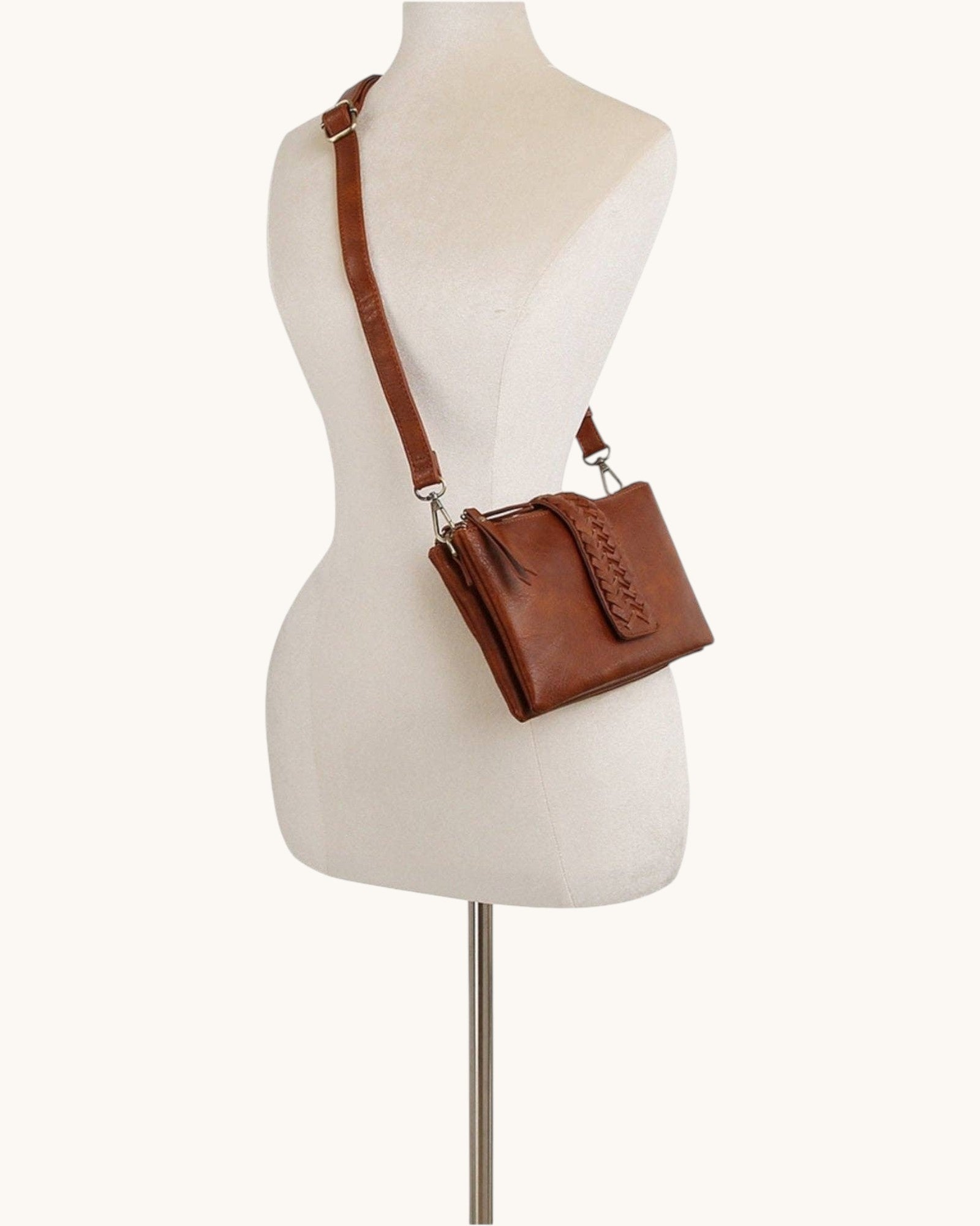 Brown leather handbag on a mannequin with a white background.