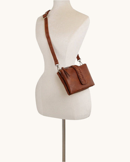 Brown leather handbag on a mannequin with a white background.