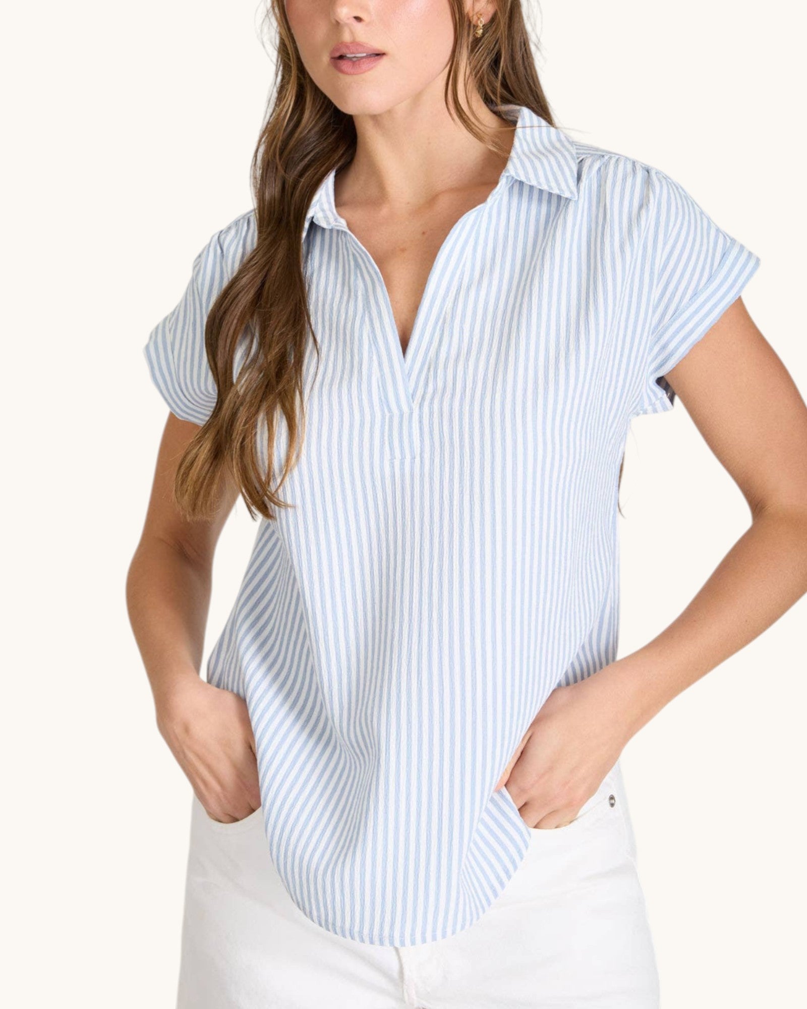 Woman wearing a light blue and white striped shirt on a white background.