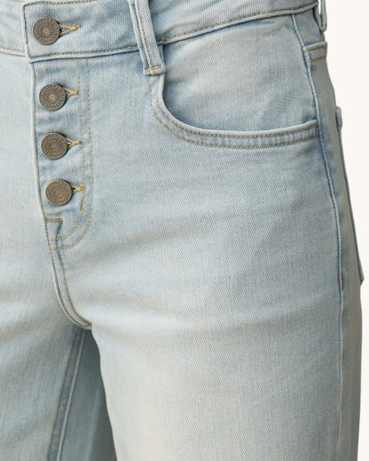 Close-up of light blue jeans with button details on a white background.