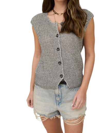 Woman wearing a gray sleeveless button-up vest and denim shorts on a white background.