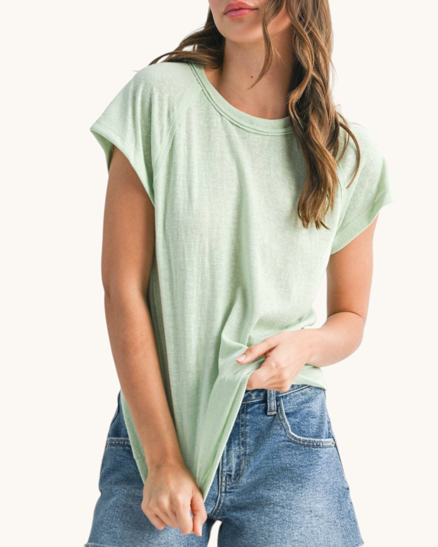 Woman wearing a casual relaxed fit baseball tee in light mint hue. 