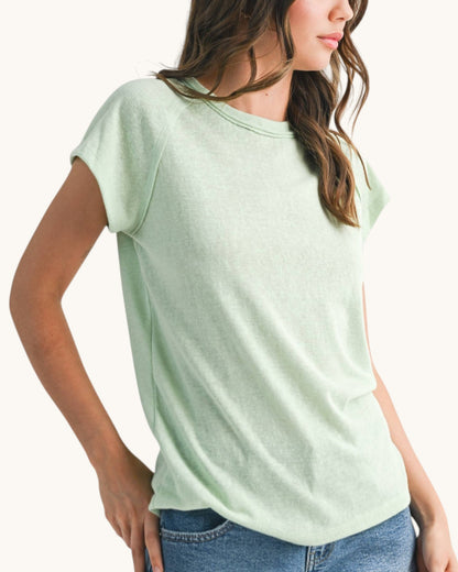Woman wearing a casual relaxed fit baseball tee in light mint hue. 