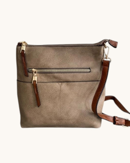 Brown leather handbag with gold zipper on a white background.