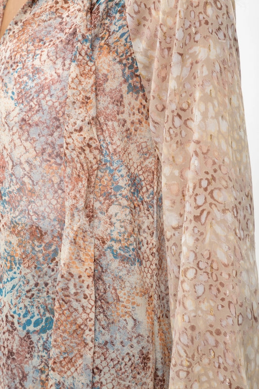 Close-up of animal print patterned fabric with earthy tones on a plain background.