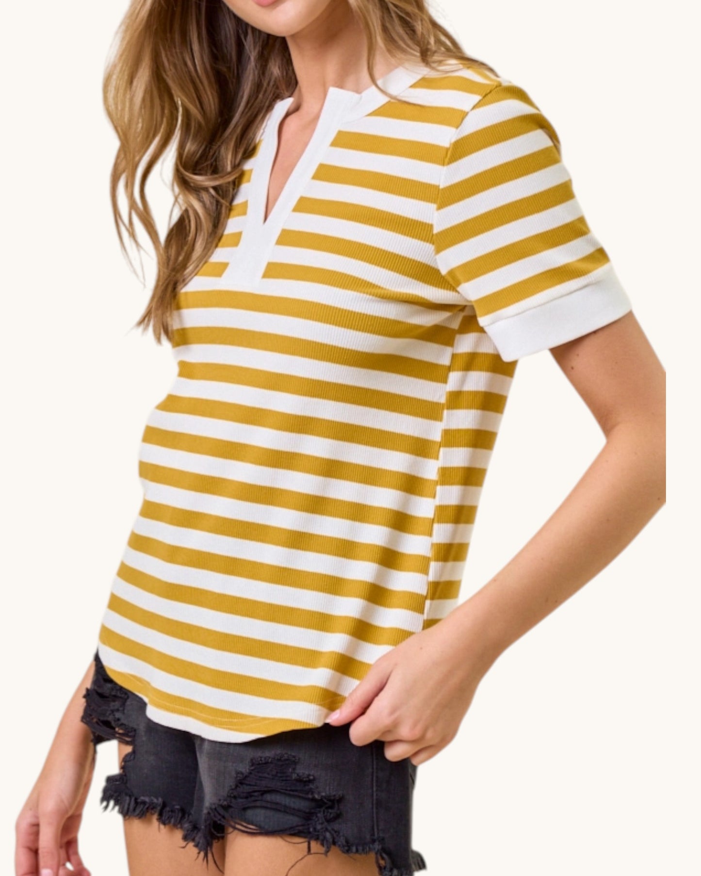 Woman wearing a yellow and white striped shirt with black shorts on a white background.