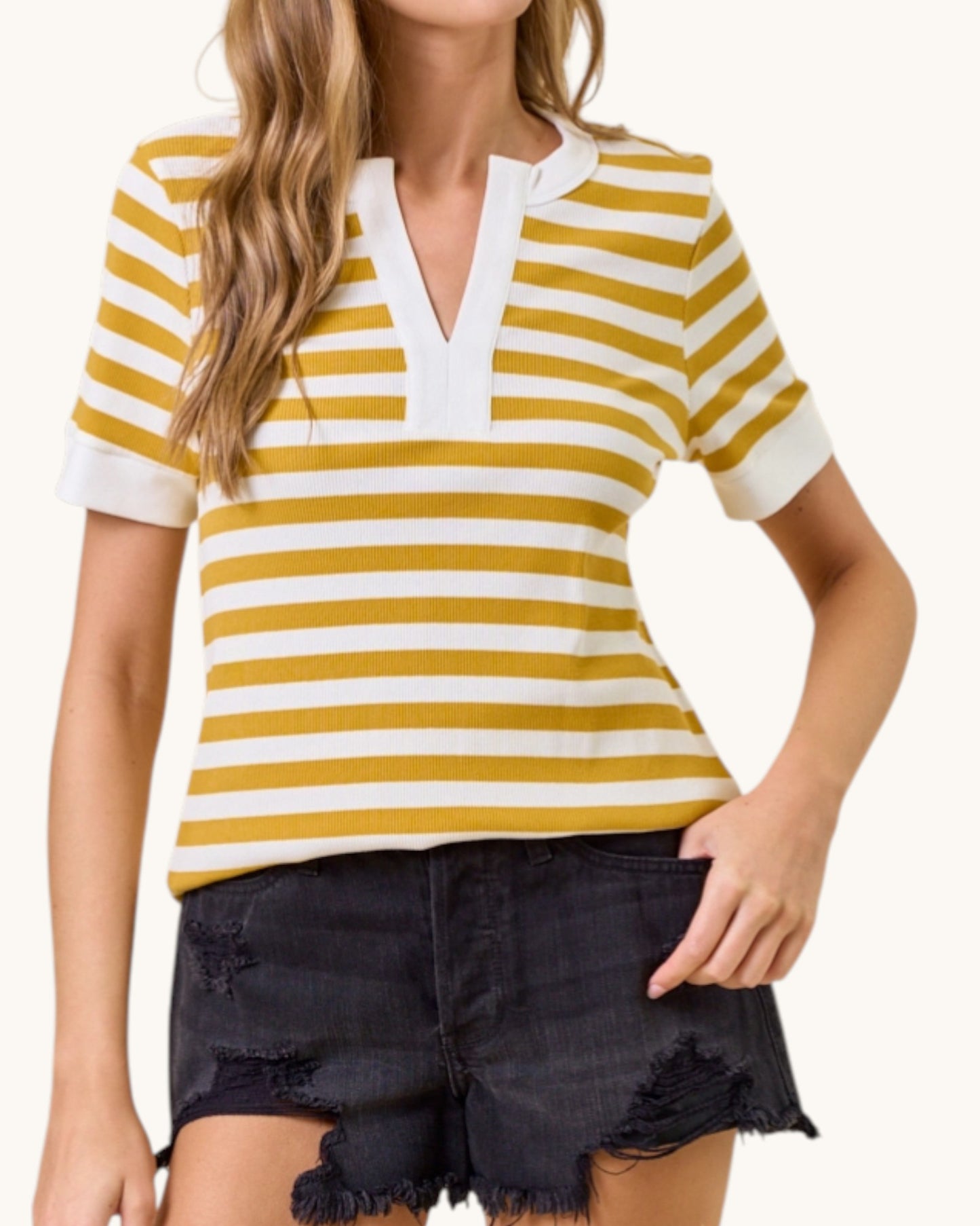 Woman wearing a yellow and white striped shirt with black shorts on a white background.