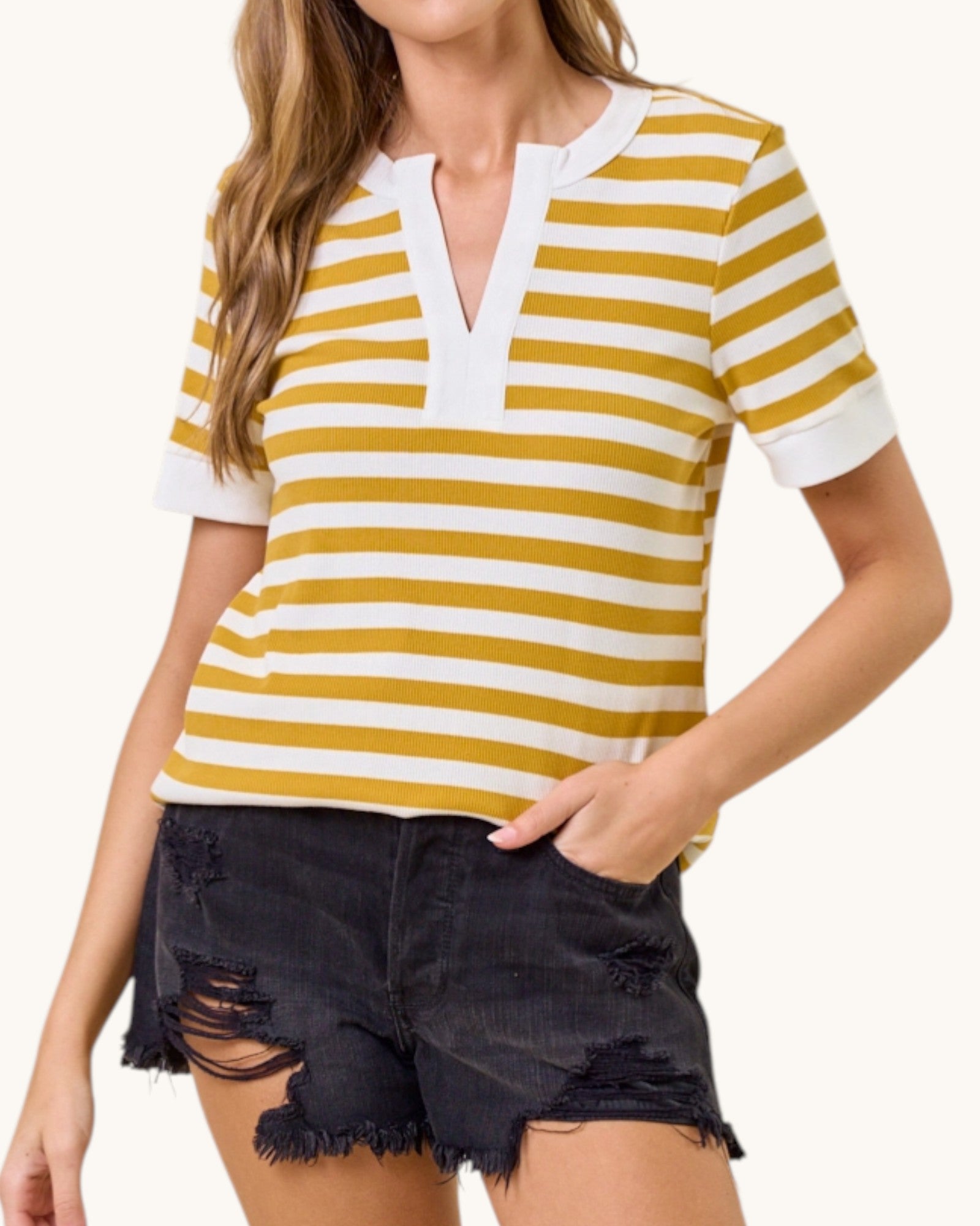 Woman wearing a yellow and white striped shirt with black shorts on a white background.