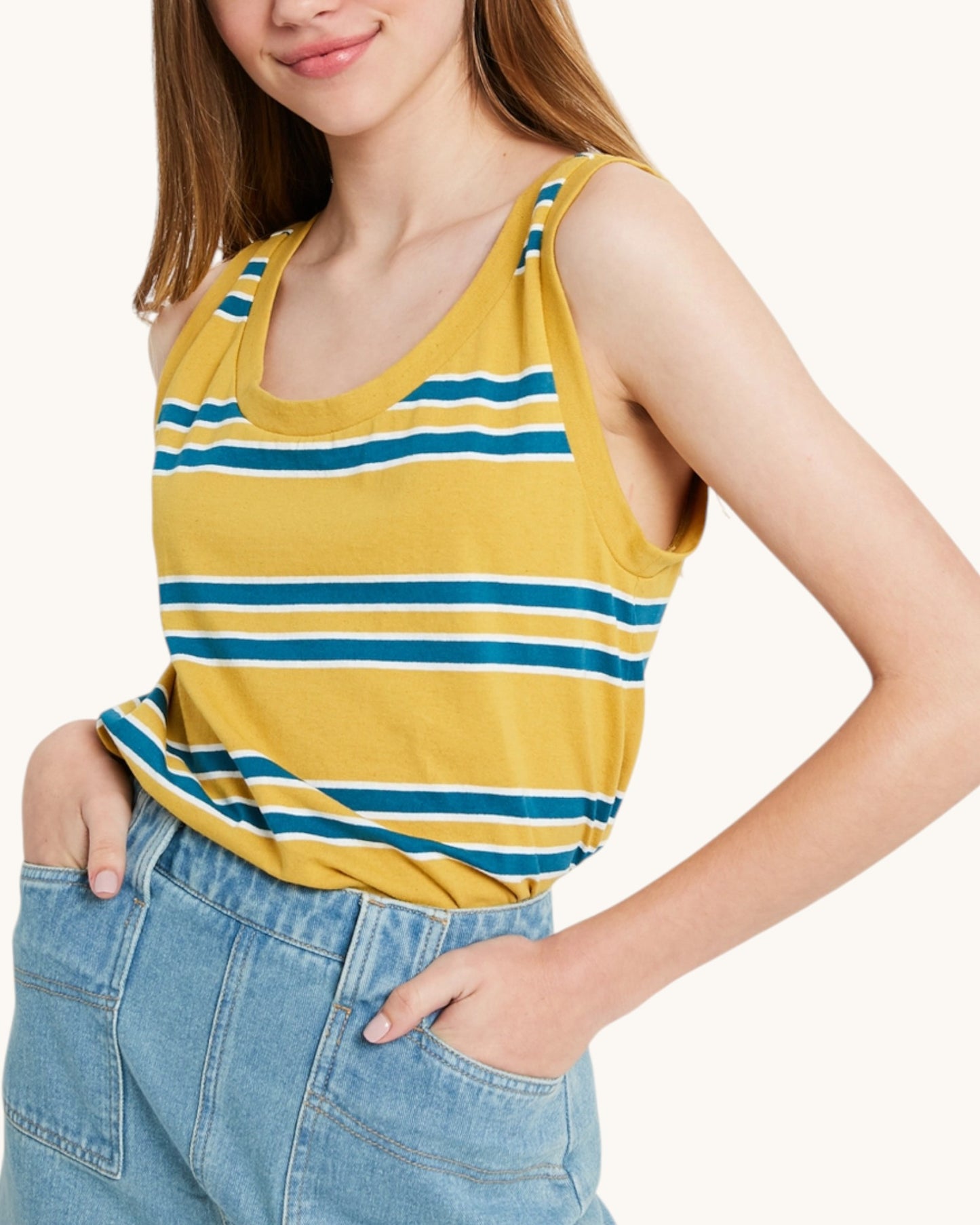 Person wearing a yellow and blue striped tank top with blue jeans on a white background.