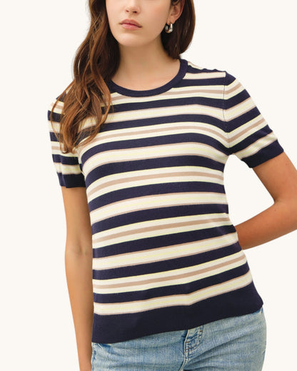 Woman wearing a navy and beige striped shirt with a plain background.