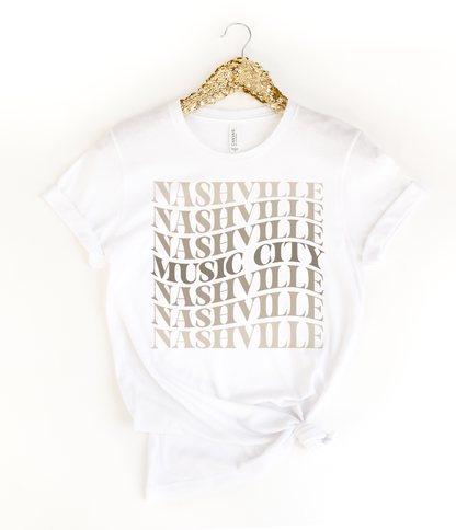  White tee with stacked “Nashville Music City” design in neutral tones. 