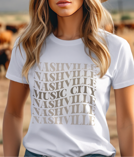  White tee with stacked “Nashville Music City” design in neutral tones. 