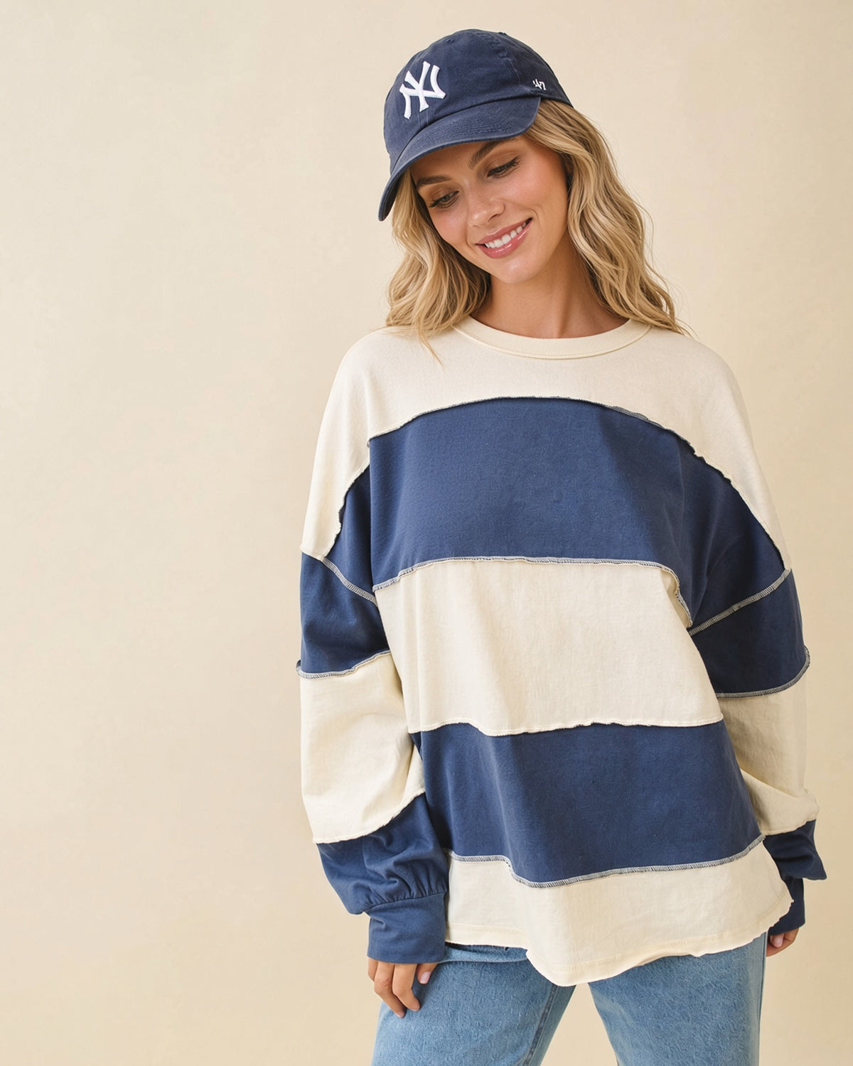 Model wearing an oversized navy and butter color block pullover with exposed seams and long sleeves.