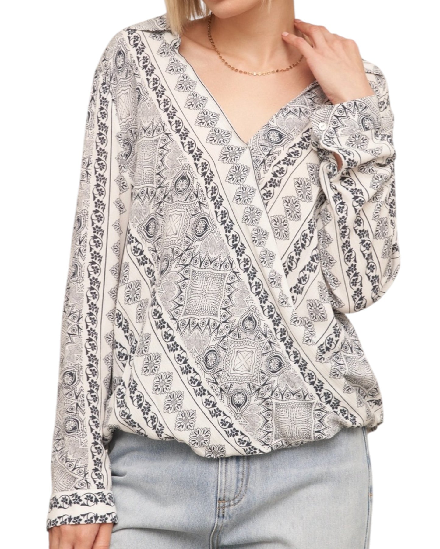 Woman wearing a patterned blouse with long sleeves on a white background.