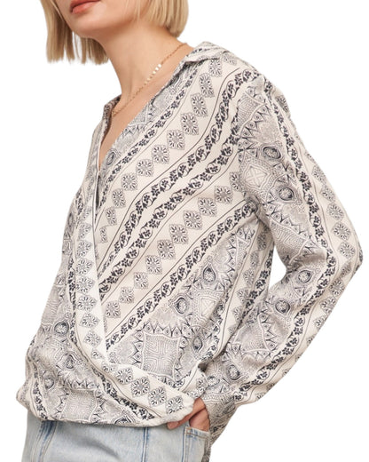 Woman wearing a patterned blouse with a white background.