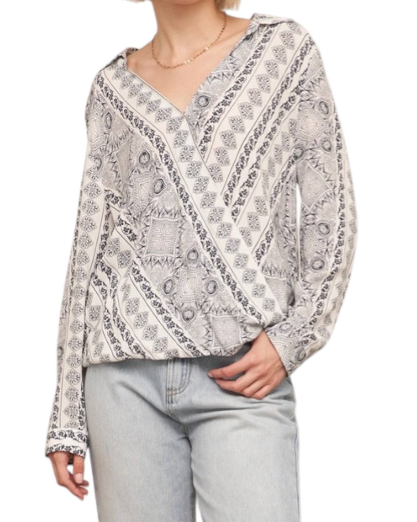 Woman wearing a ivory and navy bandana print patterned blouse and light blue jeans on a white background.