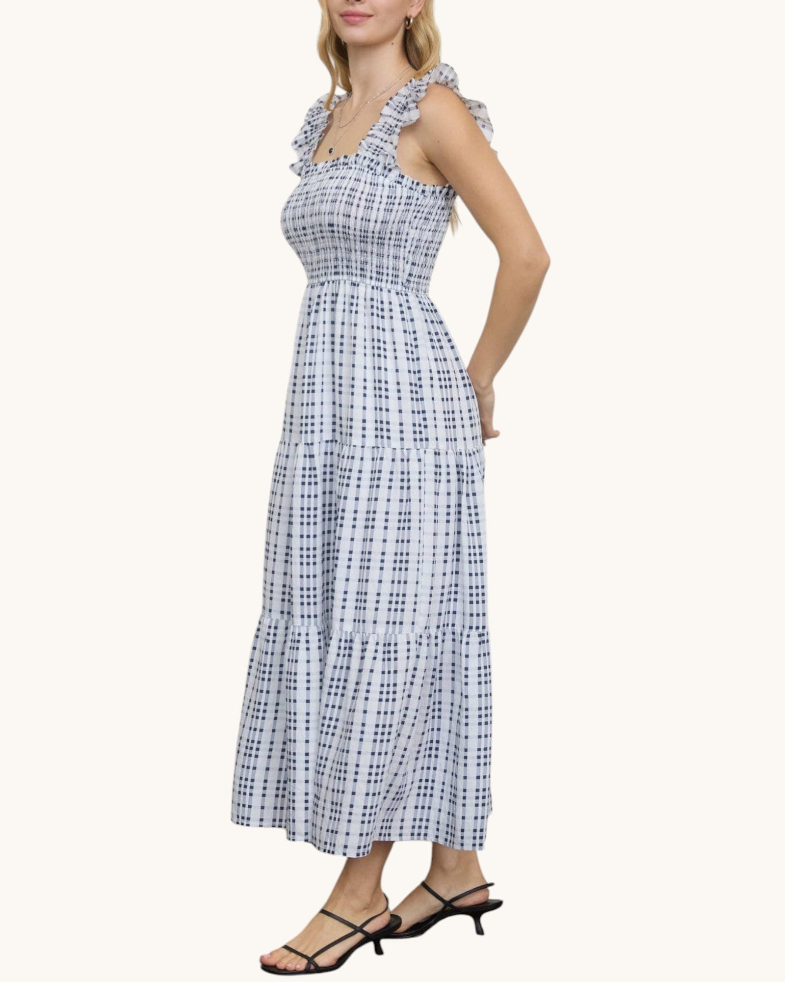 Woman wearing a blue and white checkered dress on a white background.
