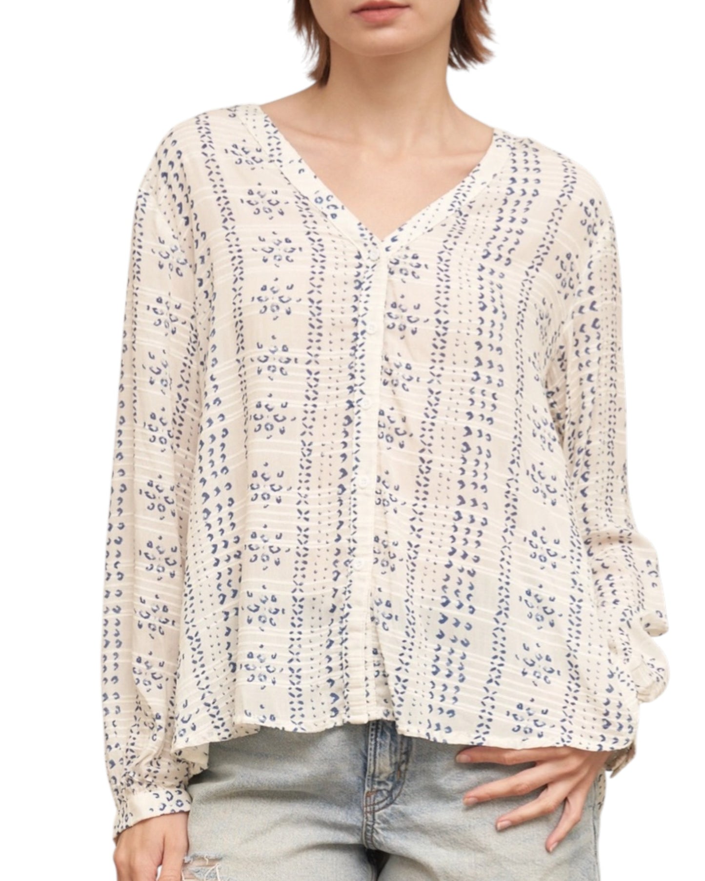 Woman wearing a textured ivory blouse with blue print and denim shorts on a white background.