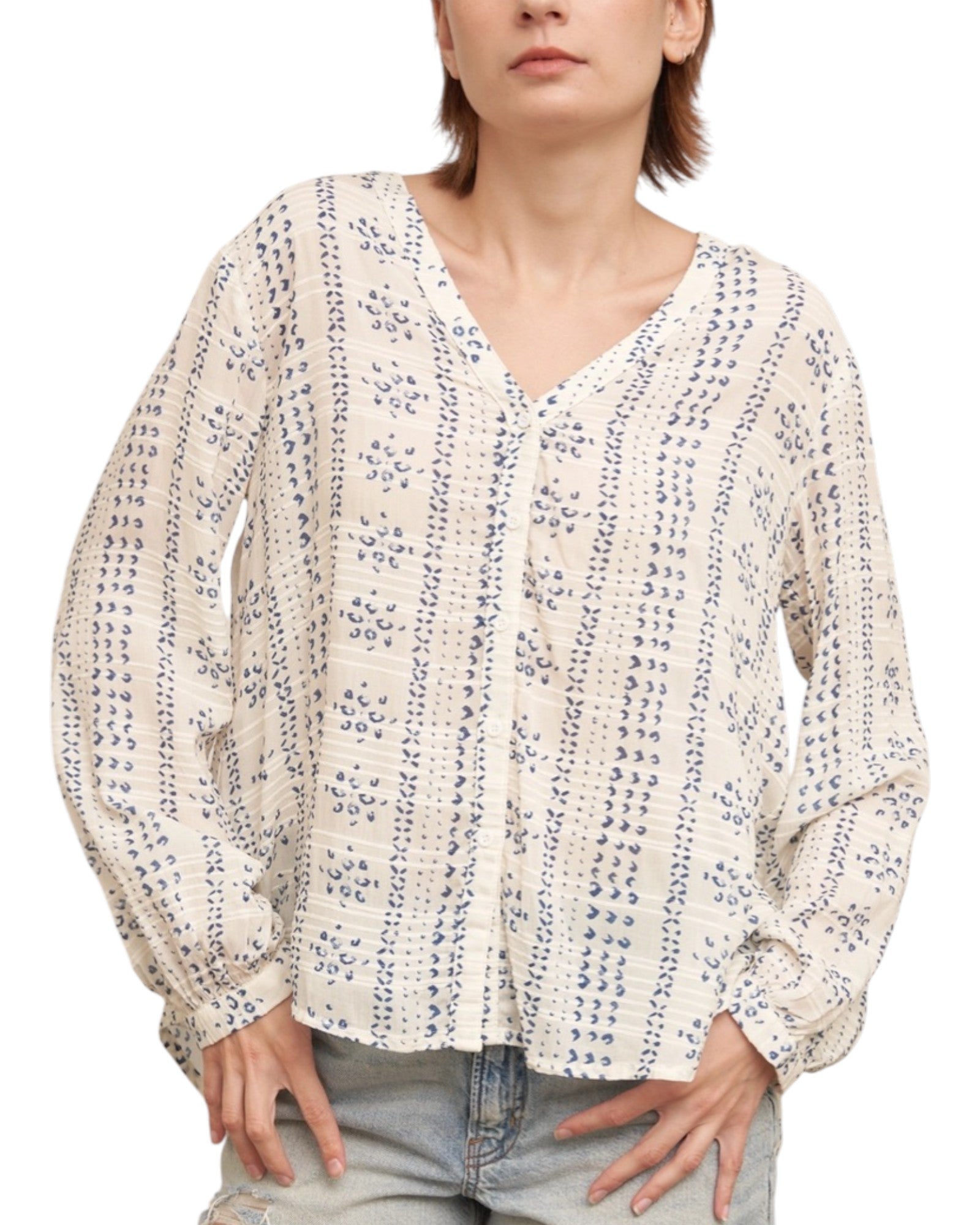 Woman wearing a textured ivory blouse with blue print and denim shorts on a white background.