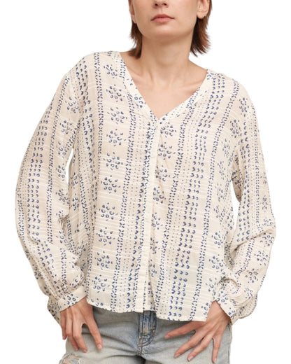 Woman wearing a textured ivory blouse with blue print and denim shorts on a white background.