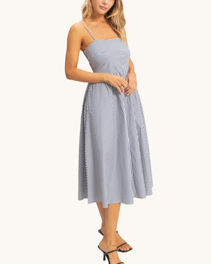 Woman wearing a navy and white striped midi dress on a white background.